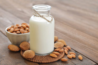 31137211 - almond milk in bottle with nuts on wooden background