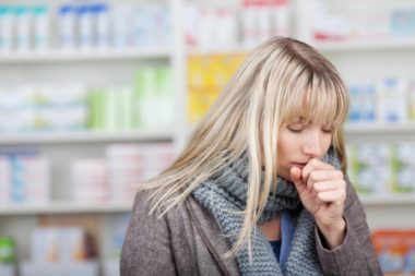 21246562 - young female customer with eyes closed coughing in pharmacy